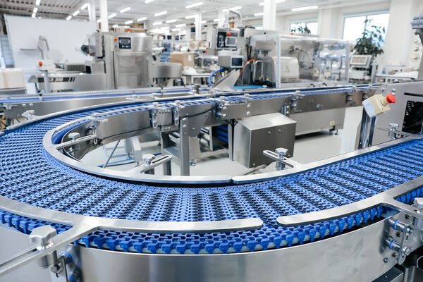 Blue modular conveyor curving through an automated food packaging hall